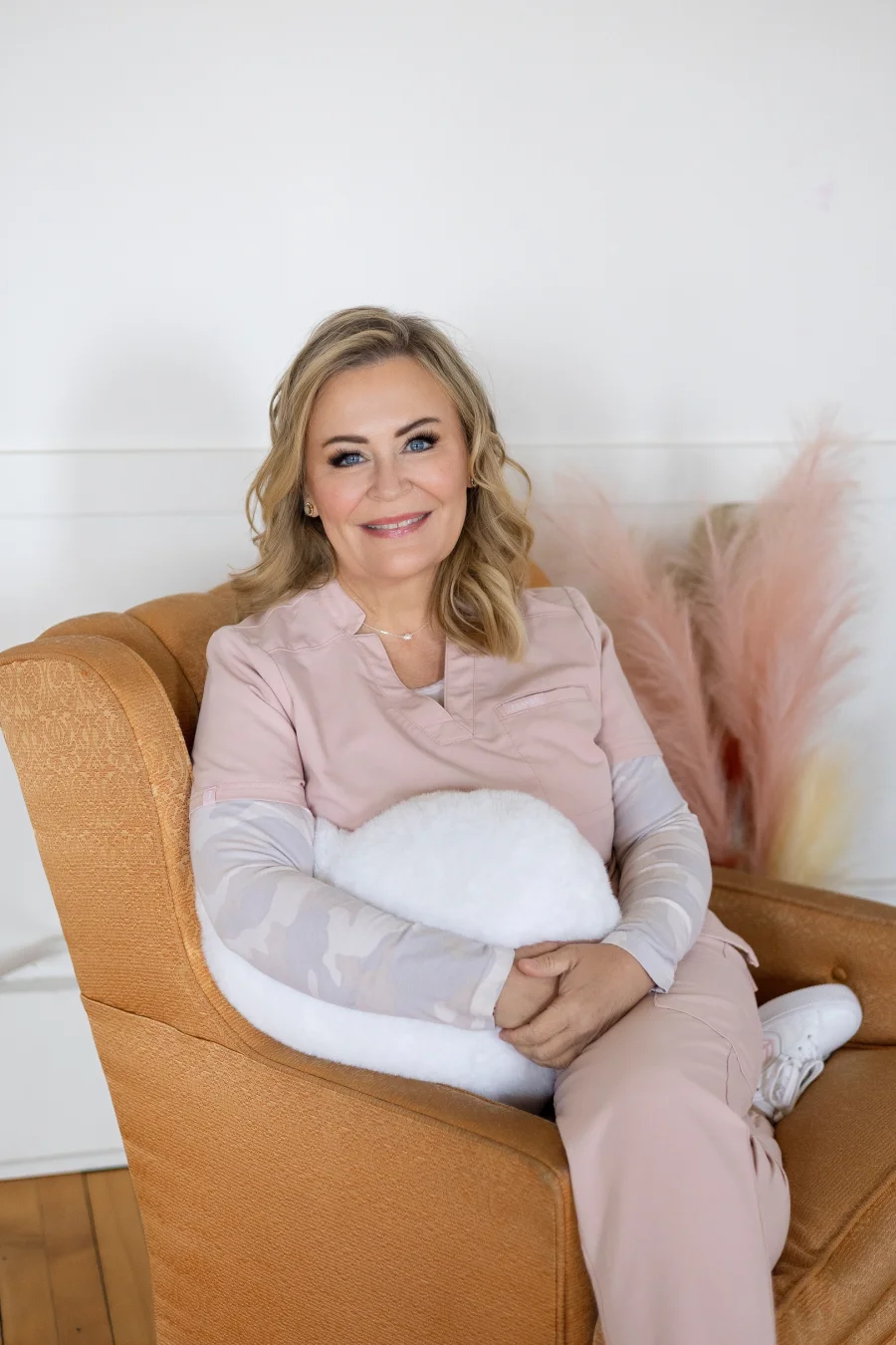 Becky Konkol, RN, owner of Ilume Aesthetics, seated in a pink top